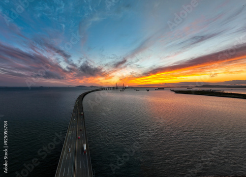 Songdo-dong, Yeonsu-gu, Incheon, South Korea - July 14, 2022: Aerial and sunset view of cars driving on the road of Incheon Bridge againt glow in the sky photo