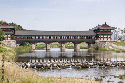 Gyeongju-si, Gyeongsangbuk-do, South Korea - June 7, 2022: Summer view of stepping stones on Namcheon Stream against Woljeonggyo Bridge with pillars and tiled roof photo