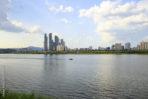 Seongsu-dong, Gwangjin-gu, Seoul, South Korea - June 11, 2022: Summer view of motor boat and a man doing water skiing on Han River against Gangbyeon Expressway and apartments