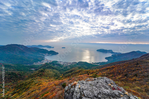 Sunrise and panoramic view of rocks and maple trees on Nojasan Mountain against village and Mongdol Beach in autumn at Hakdong-ri near Geoje-si, South Korea photo