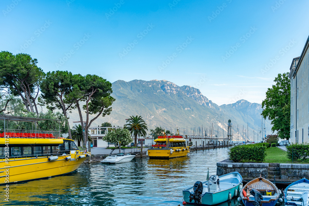 Naklejka premium small tourist port with two yellow ferries anchored in the waters of lake
