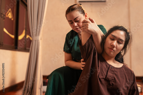 Asian woman customer received service Thai massage with professional masseur. Thai massage of shoulder stretching for treat painful from office syndrome.