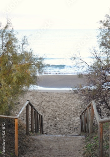 Wooden staircase going down to the sandy seashore.