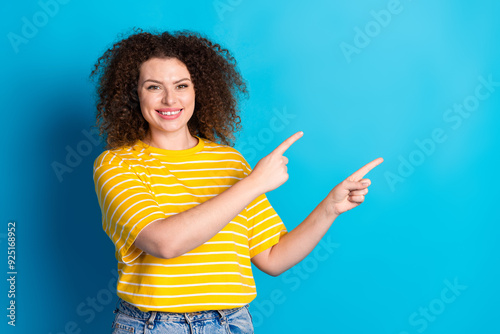 Photo portrait of attractive young woman point cheerful empty space dressed stylish striped yellow clothes isolated on blue color background