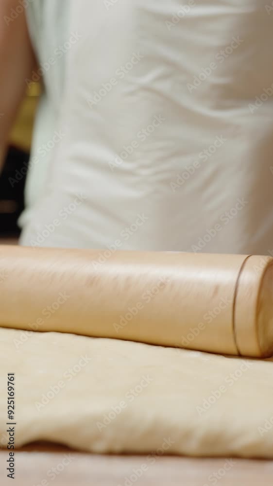 Vertical video. Rolling Out Dough with a Wooden Rolling Pin, Preparing the Dough for Baking in a Home Kitchen. Vertical video. Rolling Out Dough with a Wooden Rolling Pin, Preparing the Dough for Baking in a Home Kitchen.
