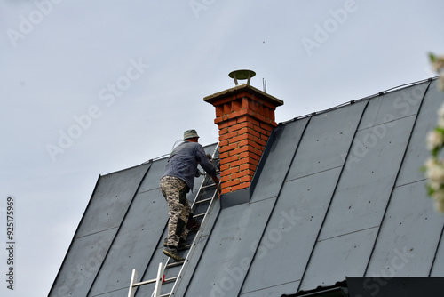 Obraz na płótnie
The roof roofer climbs up the ladder to the roof of the house to fix sheet metal roof
w salonie