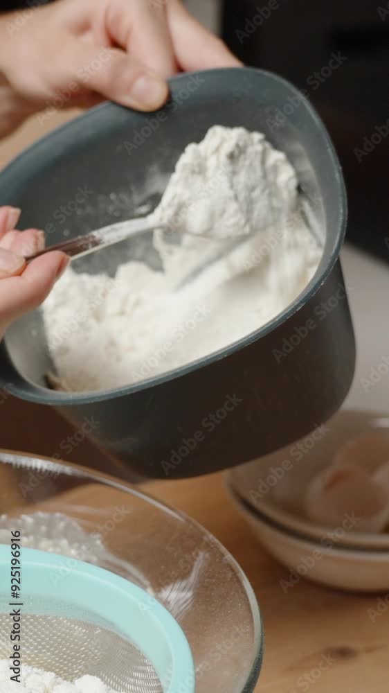 Vertical video. Sifting Flour into a Glass Bowl, Carefully Adding Ingredients for a Smooth Batter. Vertical video. Sifting Flour into a Glass Bowl, Carefully Adding Ingredients for a Smooth Batter.