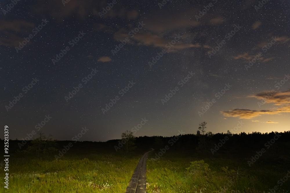 Fototapeta premium Hiking wooden trail in the Pikanomme swamp at night. Starry sky and milky way. Nature of Estonia.