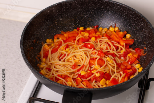 Pasta with tomato sauce in a wok on the stove.