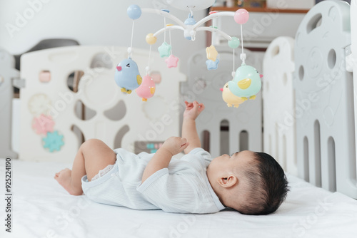 Adorable Asian Baby Boy, 5 Months Old, Smiling and Enjoy Playing with Crib Mobile in Home Playpen. photo