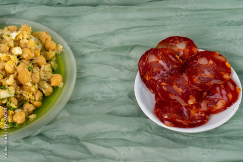 Slices of traditional Alentejo sausage (paio) and the classic Portuguese dish, chickpeas with cod, served on a catering table, ready for a delicious appetizer. photo