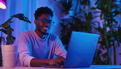 Man working on laptop in neon blue light.