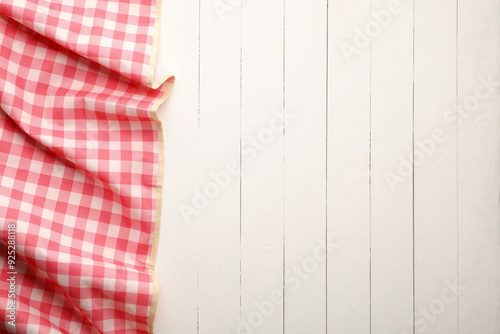 Red checkered picnic tablecloth on white wooden table, top view. Space for text