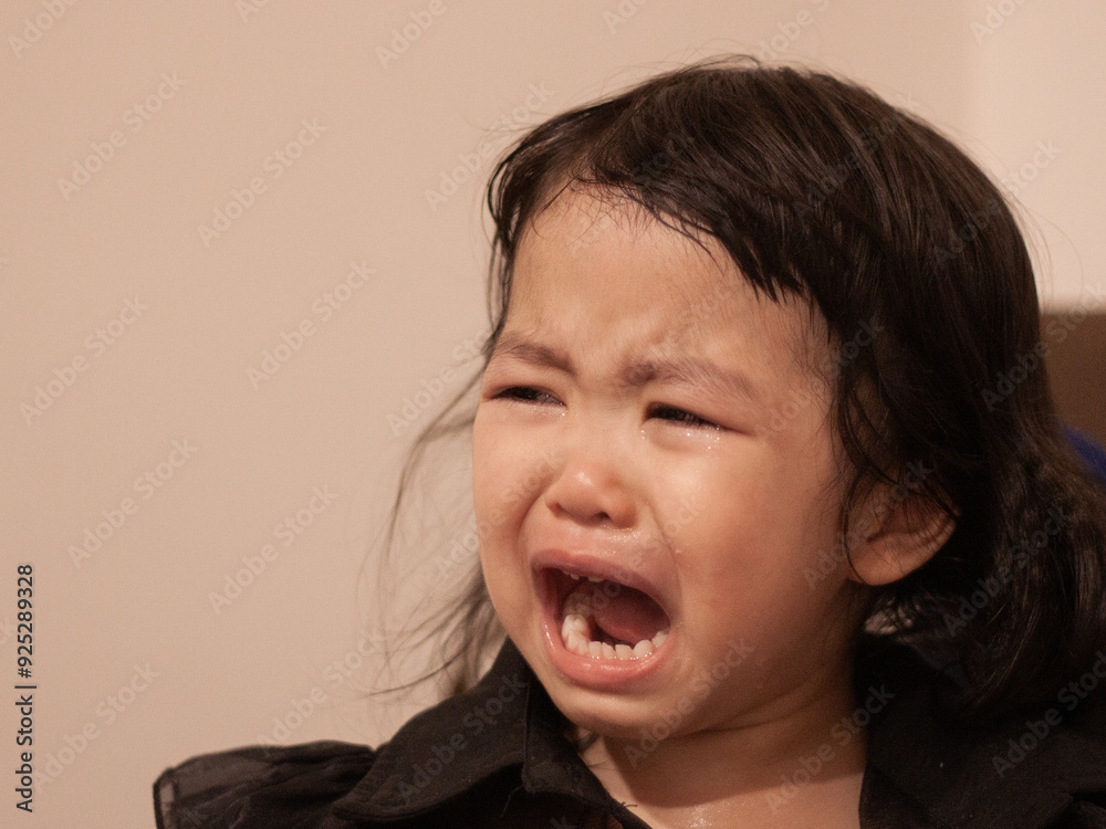 Crying asian toddler expressing strong emotions indoors Crying asian toddler expressing strong emotions indoors