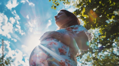 Pregnant woman enjoying outdoor sunlight, likely in springtime.