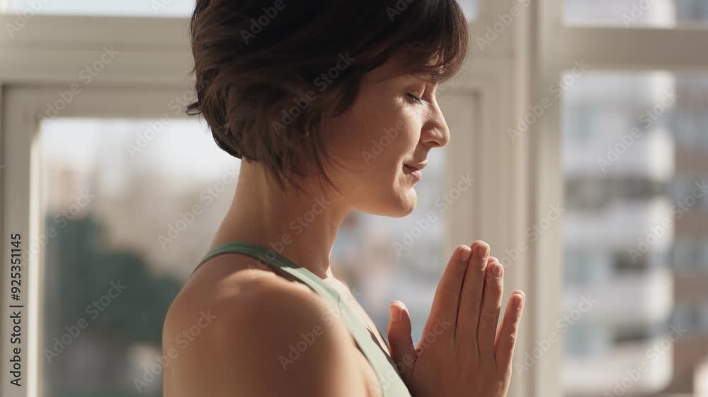 Side view of a peaceful woman practicing meditation in a sunlit room, embodying tranquility and mindfulness. Side view of a peaceful woman practicing meditation in a sunlit room, embodying tranquility and mindfulness.