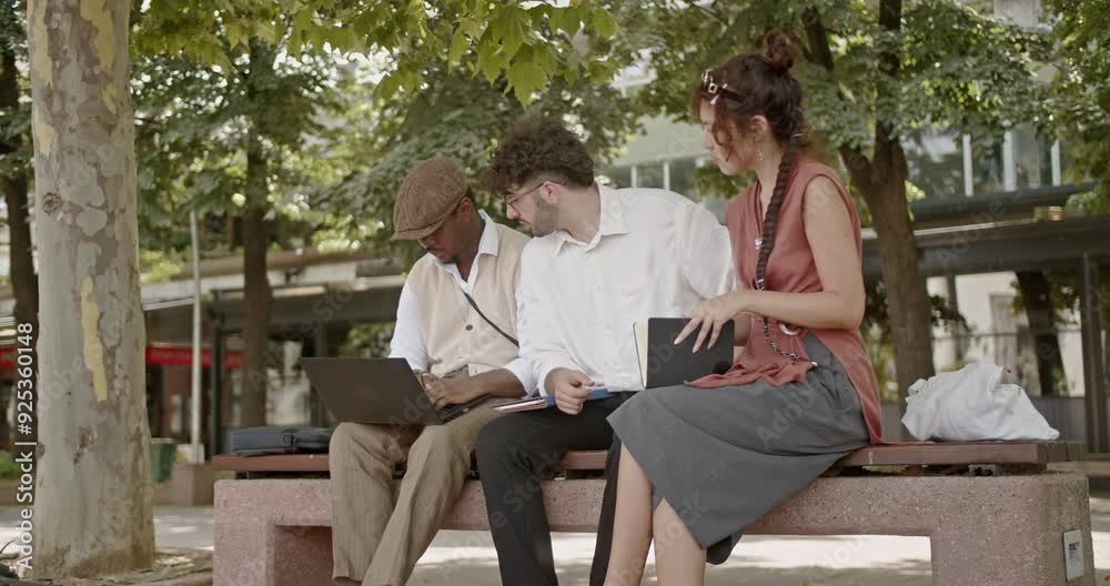 Colleagues are collaborating on a project, working together on a laptop while seated on a park bench outdoors. Their teamwork is enhanced by the serene park environment. Colleagues are collaborating on a project, working together on a laptop while seated on a park bench outdoors. Their teamwork is enhanced by the serene park environment.