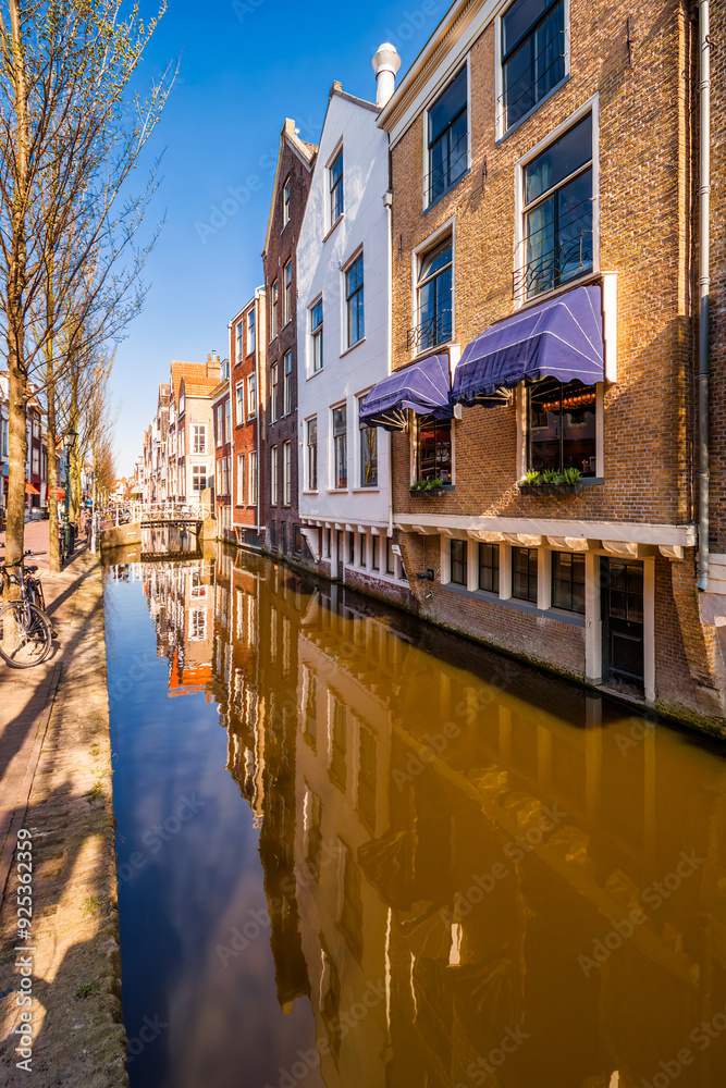 Fototapeta premium Historic buildings border a canal, along Voldersgracht street, in the old center of Delft, The Netherlands.