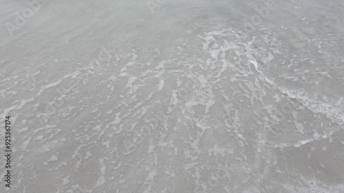 Ocean water waves on grey sand, slow-motion photo