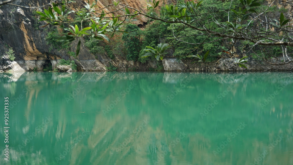 An image of a peaceful emerald-green lake with a backdrop of rocky cliffs and lush greenery. An image of a peaceful emerald-green lake with a backdrop of rocky cliffs and lush greenery.