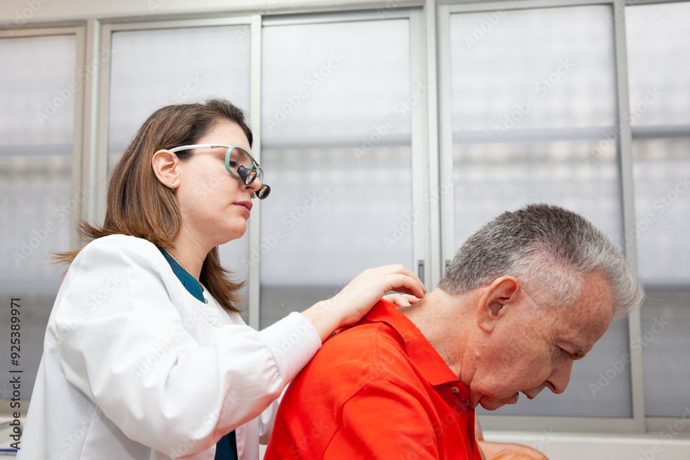 Fototapeta premium Dermatologist making a routine checkup on a senior male patient using a binocular loupe.