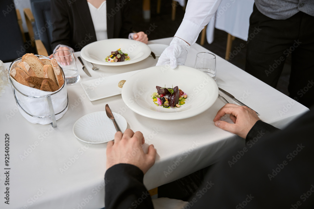 Waiter serving order to table for man and woman on date in a restaurant Waiter serving order to table for man and woman on date in a restaurant