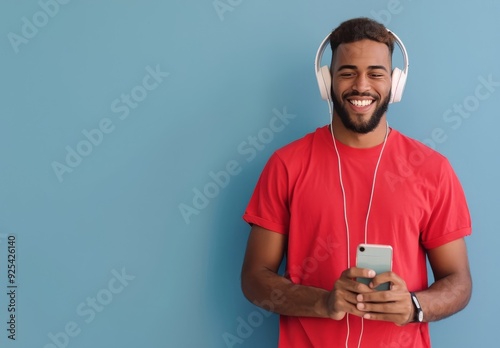 Young Man Smiling While Listening to Music on a Smartphone in a Cozy Room at ...