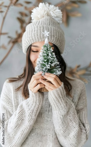Woman Holding Miniature Christmas Tree and Gift Near Festive Decoration
