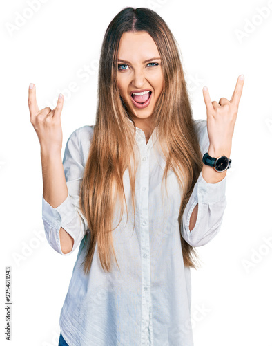 Beautiful caucasian woman wearing casual white shirt shouting with crazy expression doing rock symbol with hands up. music star. heavy music concept.