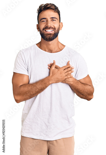 Obraz na płótnie Young hispanic man wearing casual white tshirt smiling with hands on chest with closed eyes and grateful gesture on face