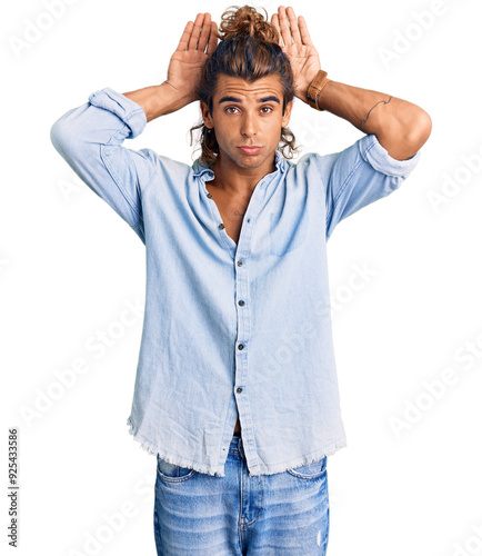 Young hispanic man wearing summer style doing bunny ears gesture with hands palms looking cynical and skeptical. easter rabbit concept.