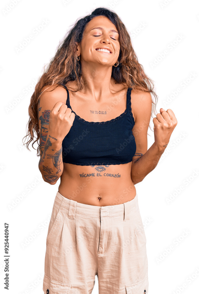 Φωτογραφία Young hispanic woman with tattoo wearing casual clothes excited for success with arms raised and eyes closed celebrating victory smiling