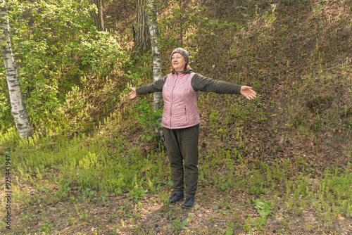 Person standing with arms open in a lush green forest during daylight