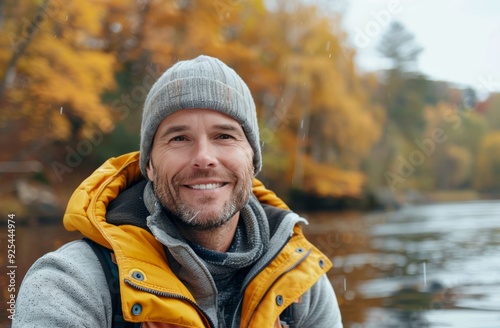 Smiling Man in Yellow Jacket Enjoying Autumn by the River