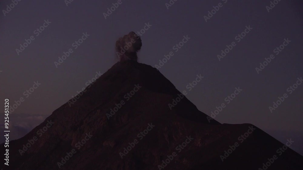 Volcán Fuego erupts at dawn above the clouds in Guatemala. Smoke and lava shoot out of the volcano as we zoom out