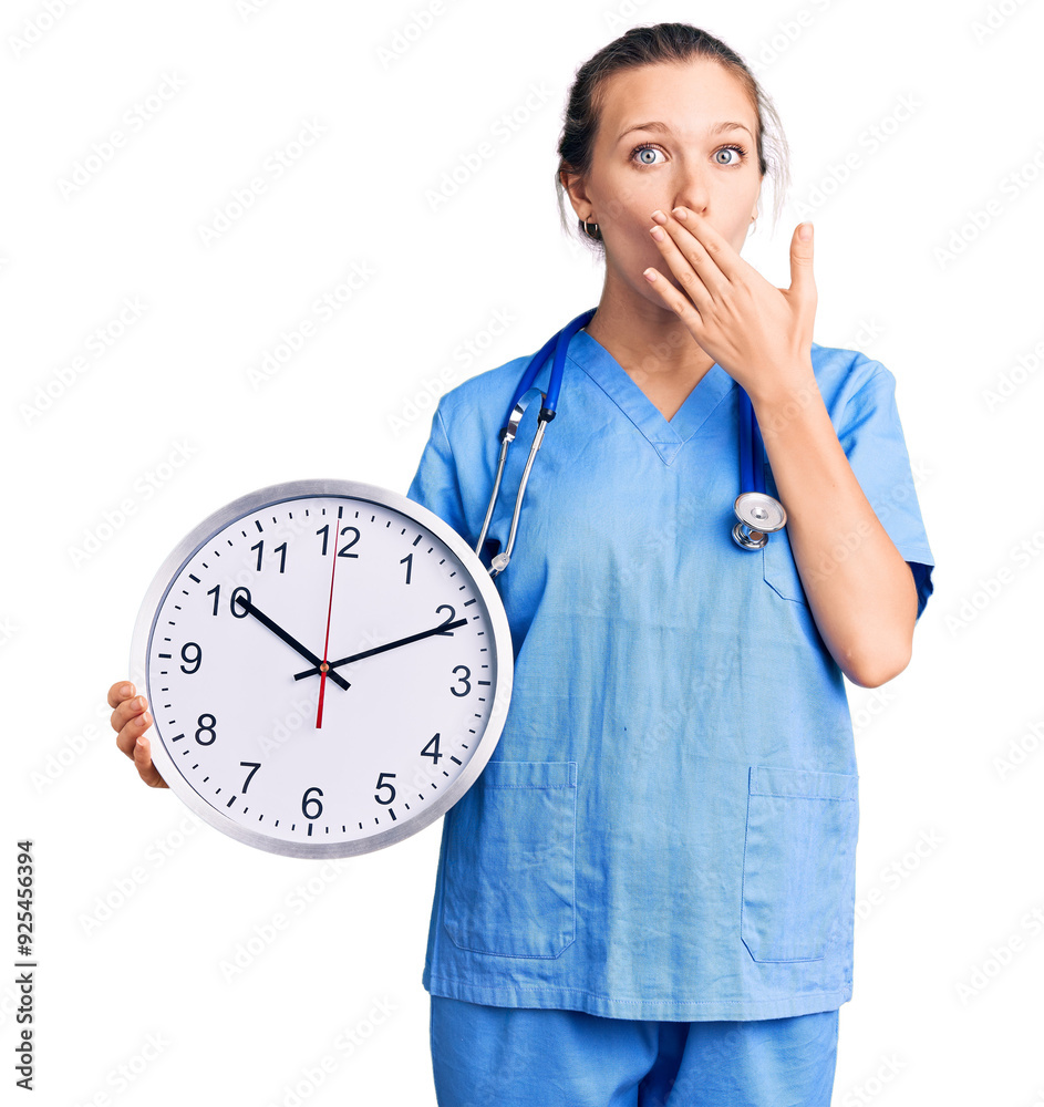 Young beautiful blonde woman wearing doctor uniform and stethoscope covering mouth with hand, shocked and afraid for mistake. surprised expression Young beautiful blonde woman wearing doctor uniform and stethoscope covering mouth with hand, shocked and afraid for mistake. surprised expression