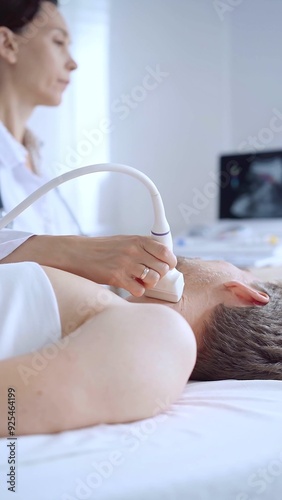 Doctor woman performing neck ultrasound exam on male patient. Medicine service concept