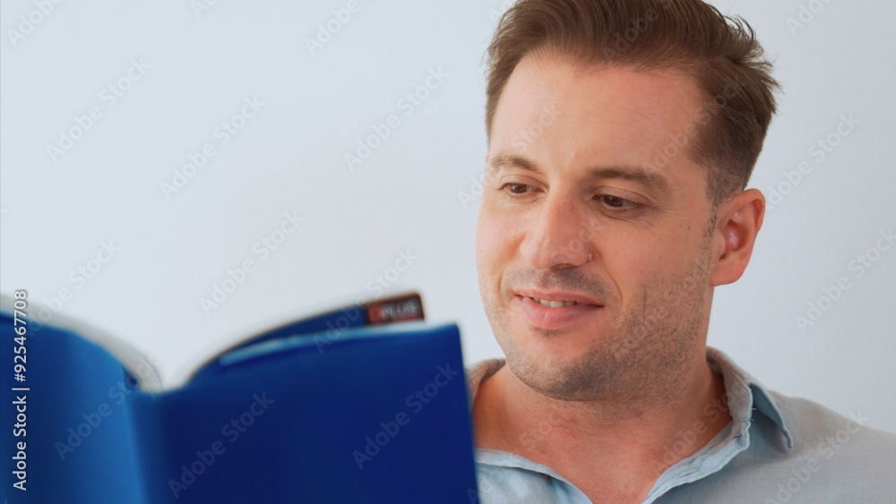 Middle age man sitting on sofa read textbook increase knowledge about social and technology for occupation or raise children to be good adult as smart father. Lifelong learning concept. Divergence. Middle age man sitting on sofa read textbook increase knowledge about social and technology for occupation or raise children to be good adult as smart father. Lifelong learning concept. Divergence.