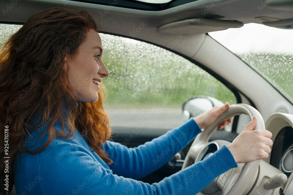 Woman Driving Car on Rainy Day While Smiling in Suburban Area
