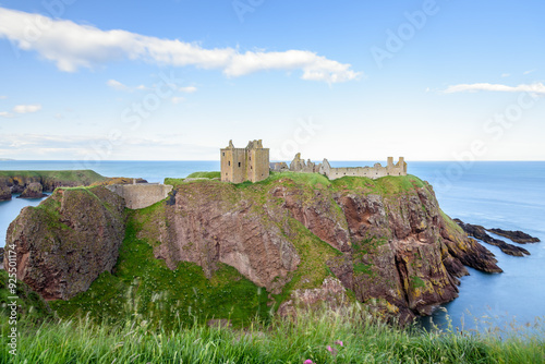 View of Dunnottar Clastle perched on a rocky outcrop on the coast of Aberdeenshire, Scotland,  on a clear summer day photo