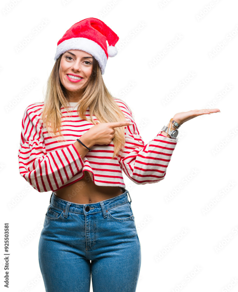Young beautiful woman wearing christmas hat over isolated background amazed and smiling to the camera while presenting with hand and pointing with finger. Young beautiful woman wearing christmas hat over isolated background amazed and smiling to the camera while presenting with hand and pointing with finger.