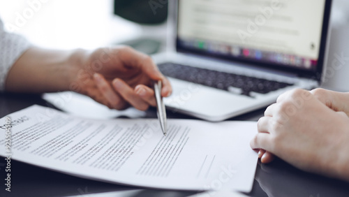 Business people sitting and discussing contract in office, closeup. Partners or lawyers working together at meeting before signing papers. Teamwork and partnership