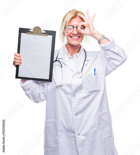 Middle age blonde doctor woman holding clipboard over isolated background with happy face smiling doing ok sign with hand on eye looking through fingers