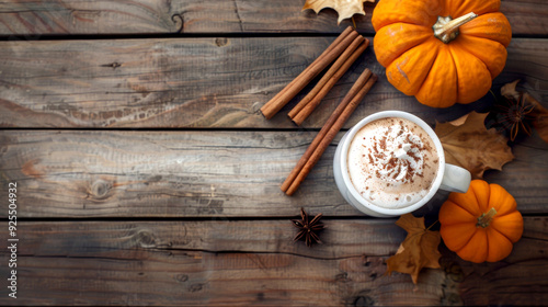 Fototapeta Naklejka Na Ścianę i Meble -  Cozy autumn scene featuring pumpkin spice latte topped with whipped cream and cinnamon, surrounded by pumpkins, cinnamon sticks, and autumn leaves on rustic wooden table.