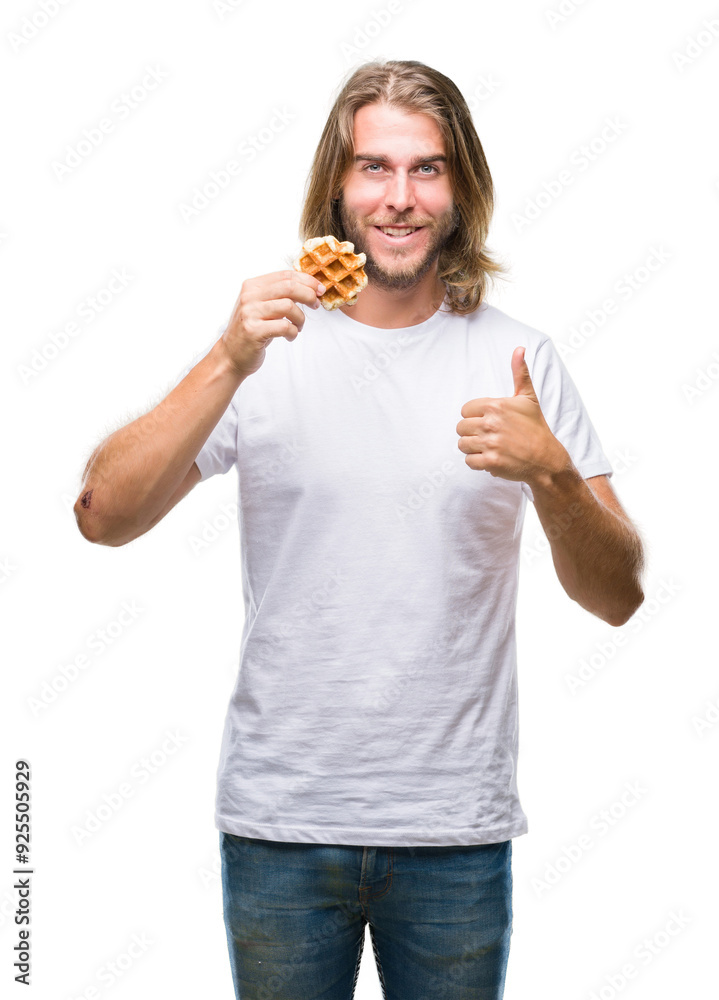 Young handsome man with long hair over isolated background eating waffle happy with big smile doing ok sign, thumb up with fingers, excellent sign Young handsome man with long hair over isolated background eating waffle happy with big smile doing ok sign, thumb up with fingers, excellent sign