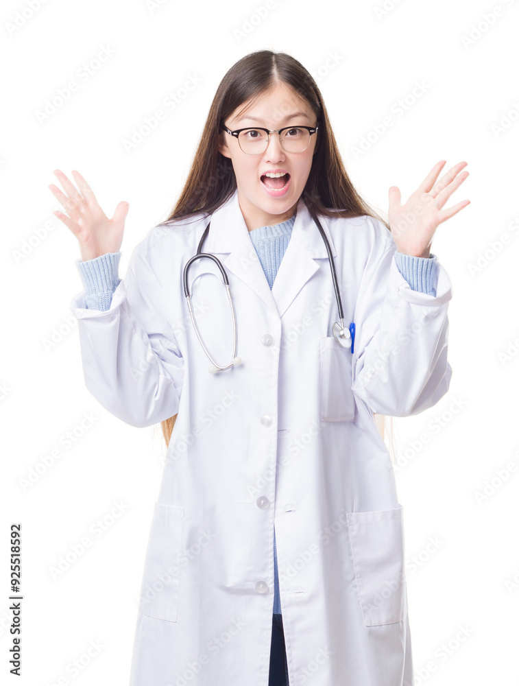 Young Chinese doctor woman over isolated background celebrating crazy and amazed for success with arms raised and open eyes screaming excited. Winner concept Young Chinese doctor woman over isolated background celebrating crazy and amazed for success with arms raised and open eyes screaming excited. Winner concept