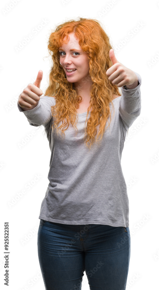 Young redhead woman approving doing positive gesture with hand, thumbs up smiling and happy for success. Looking at the camera, winner gesture. Young redhead woman approving doing positive gesture with hand, thumbs up smiling and happy for success. Looking at the camera, winner gesture.
