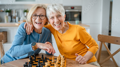 Obraz na plátně two women mature senior females sisters play chess board game at home