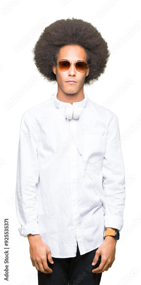 Young african american man with afro hair wearing sunglasses and headphones with serious expression on face. Simple and natural looking at the camera. Young african american man with afro hair wearing sunglasses and headphones with serious expression on face. Simple and natural looking at the camera.
