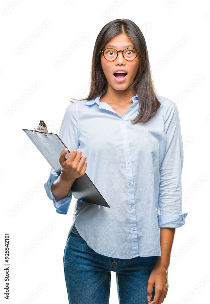Young asian business woman over isolated background holding clipboard scared in shock with a surprise face, afraid and excited with fear expression Young asian business woman over isolated background holding clipboard scared in shock with a surprise face, afraid and excited with fear expression